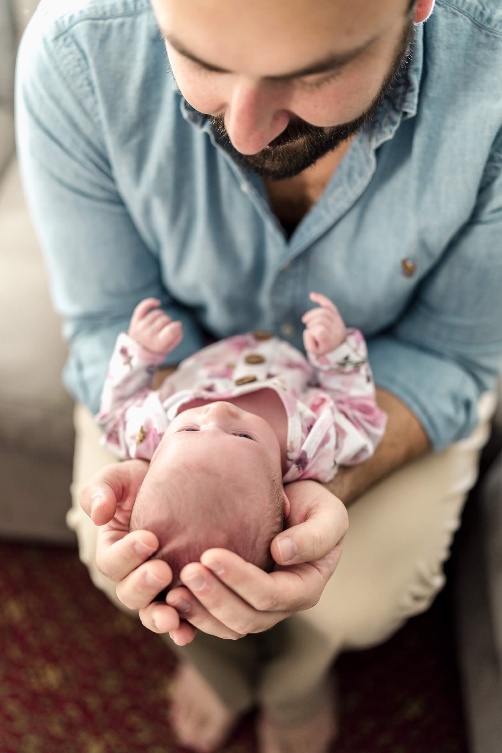 Father looks at his newborn daughter in his hands