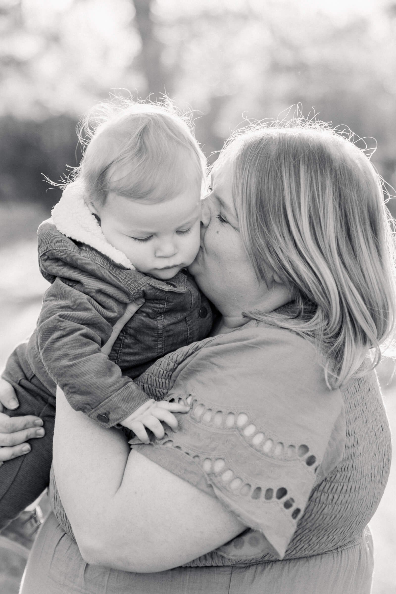 black and white photo of mother kissing her son on the cheek