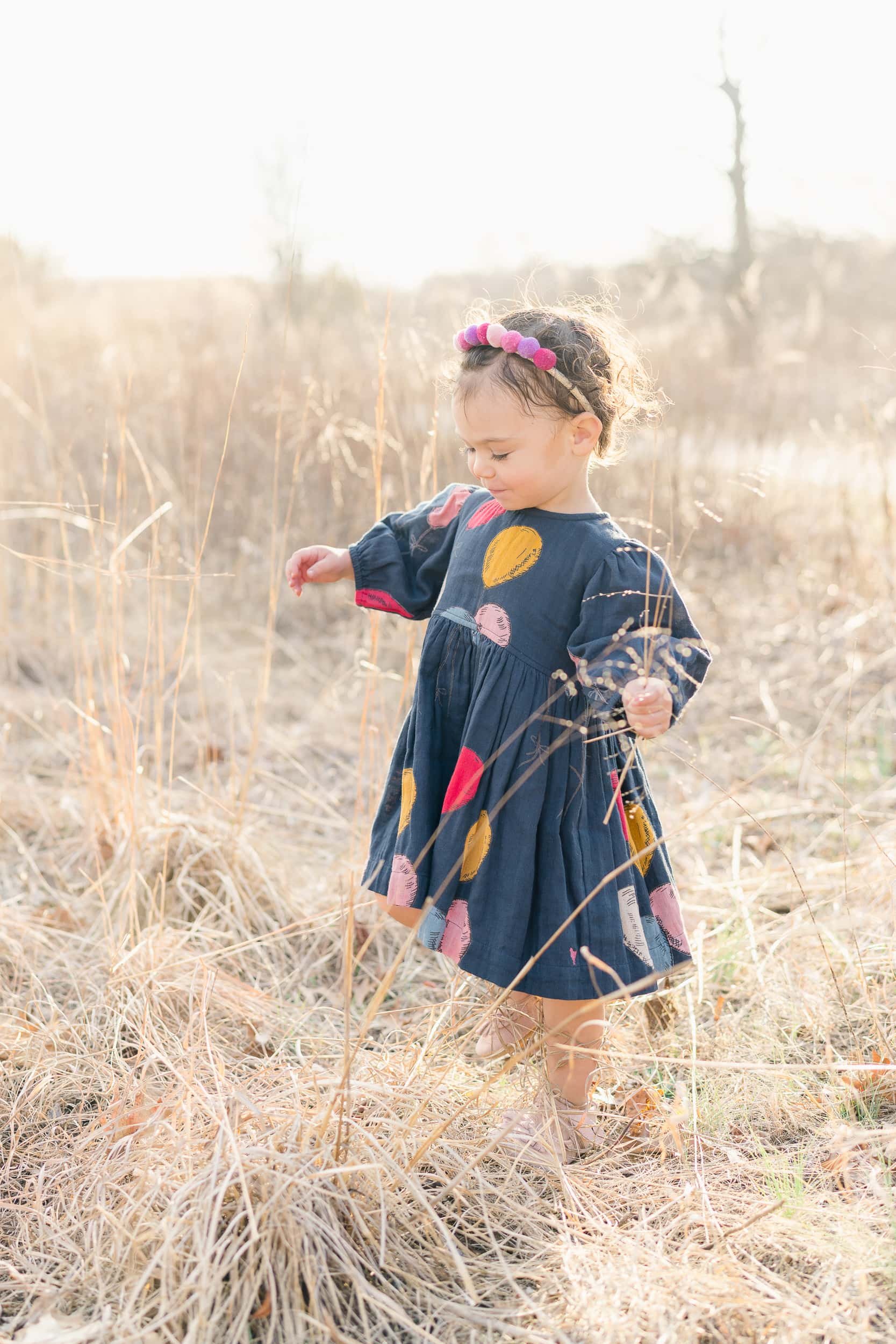 A little girl plays with the tall grasses in a field by Moorestown Family Photographer Courtney Landrum.