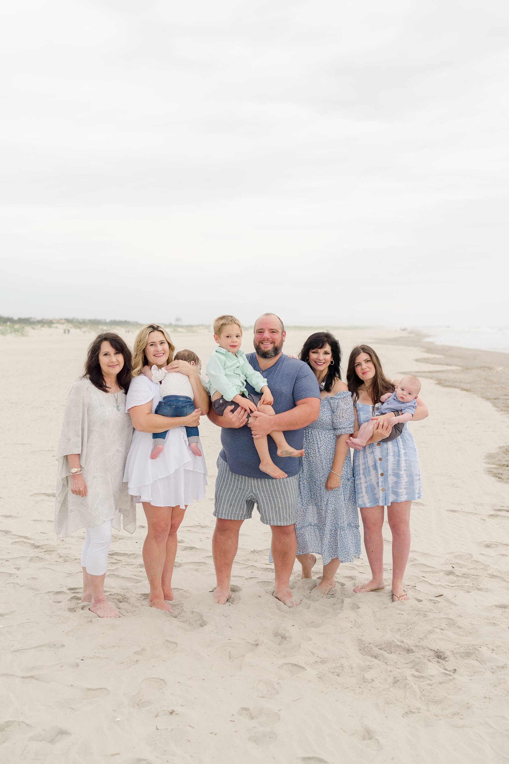 Family wearing blue and white poses on the beach for an extended family photoshoot in Avalon, NJ.