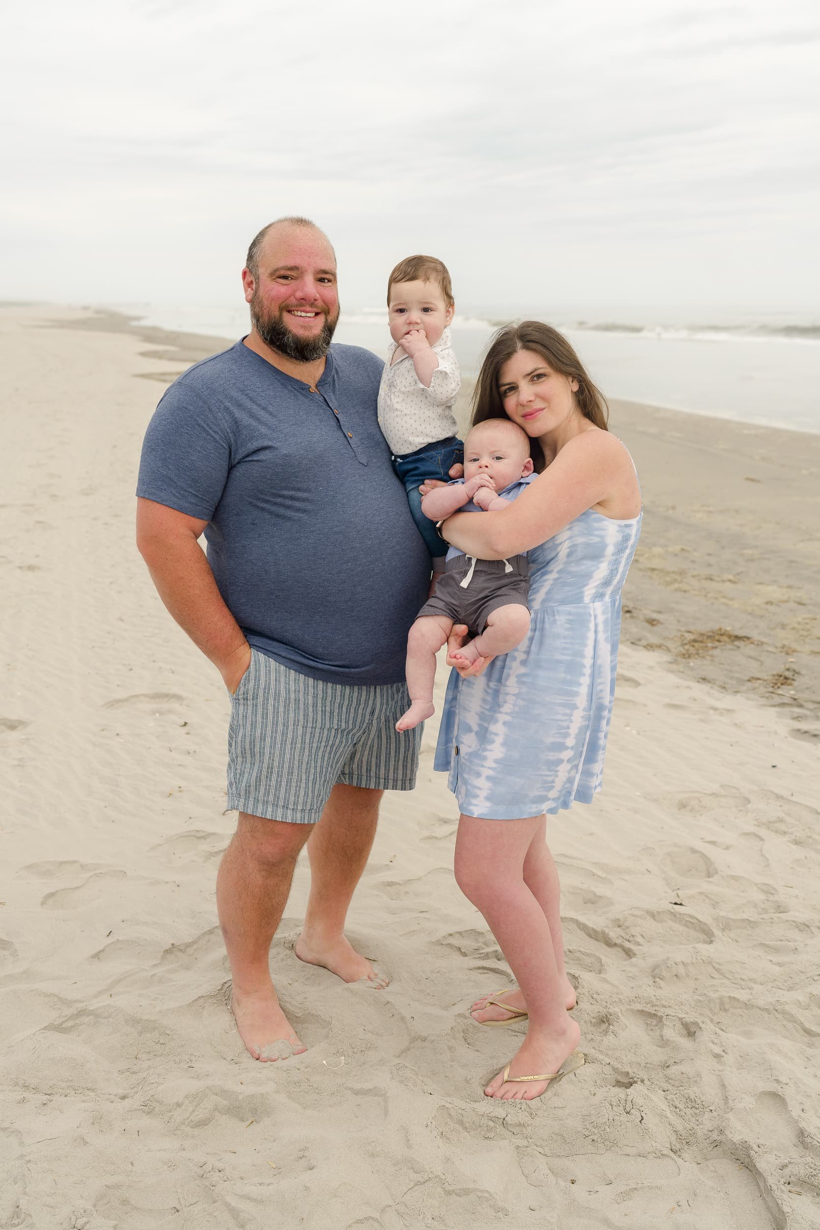 A brother and sister pose each with their newborn babies on the beach in New Jersey.