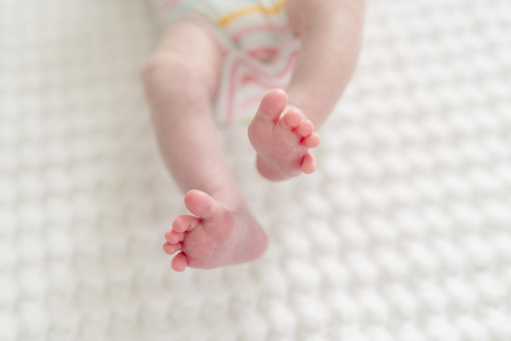A detail shot of tiny newborn feet stretching.