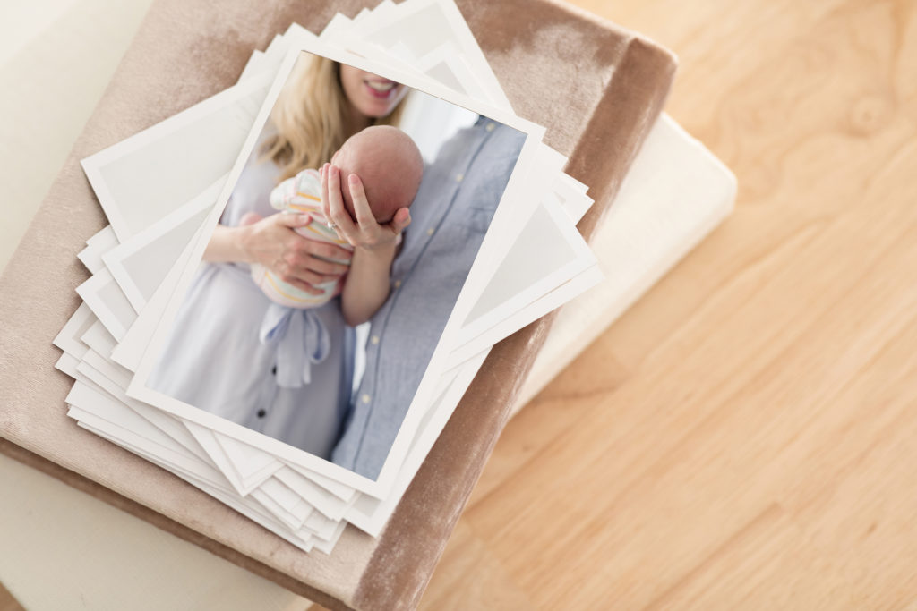 A stack of printed photographs from a maternity and newborn photography package.
