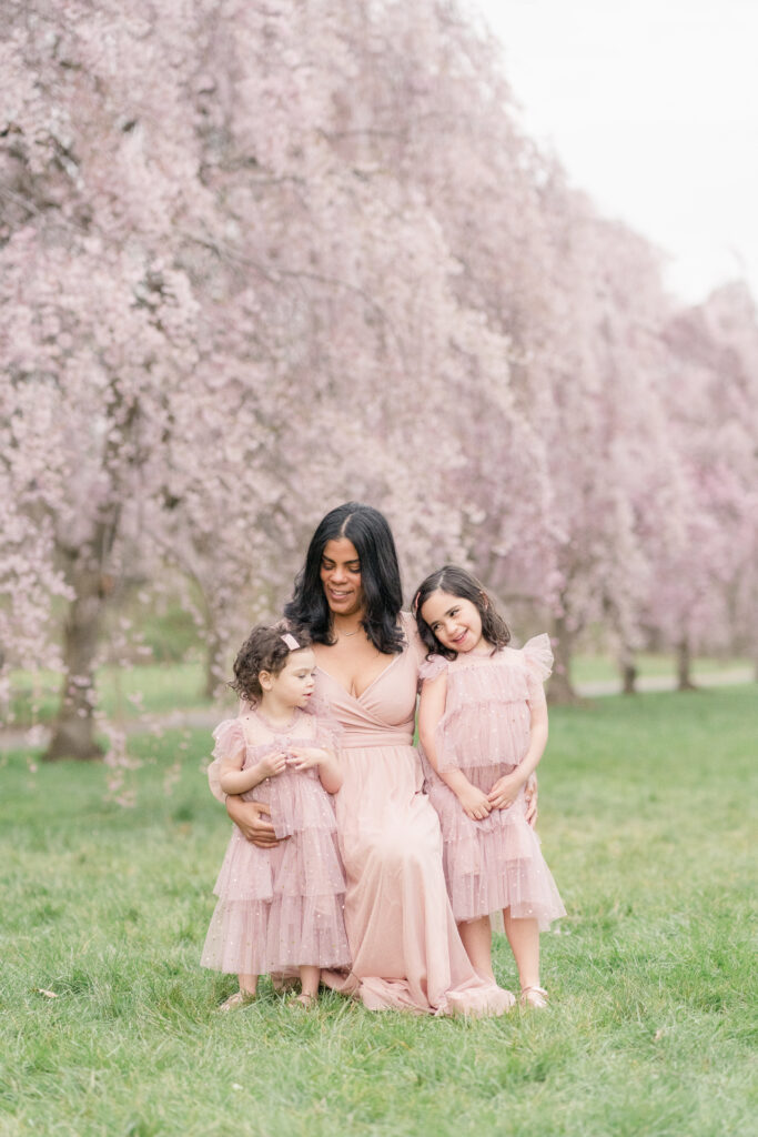 A mother and her daughters pose in front of the cherry blossom trees in full bloom.