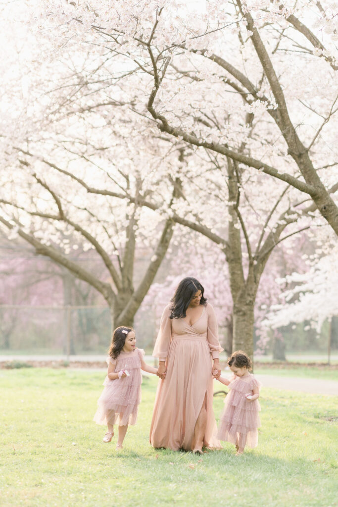 A mom and her two daughters walk through the cherry blossom trees at Fairmount Park in Philadelphia.
