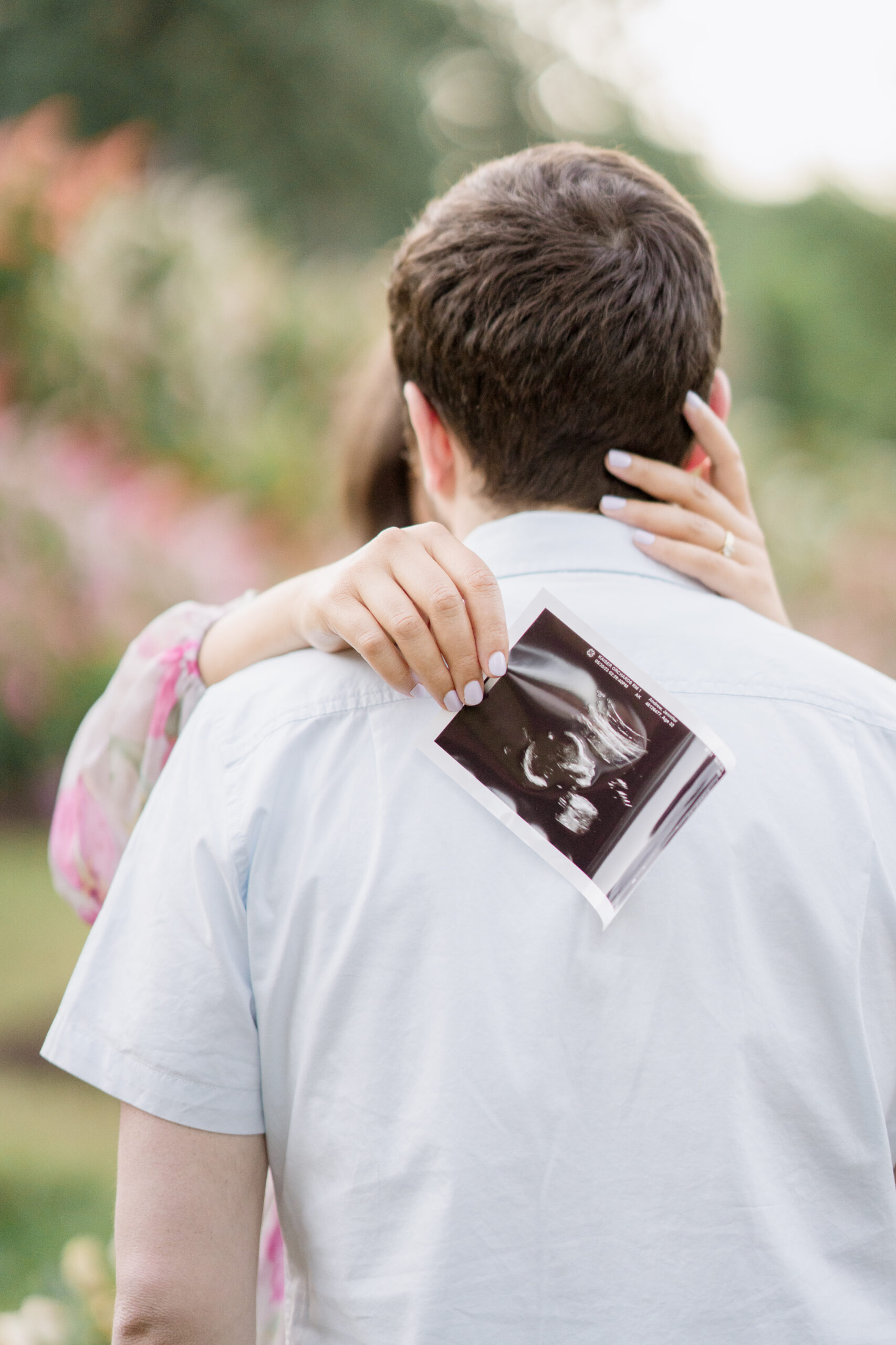 A pose with the mom holding an ultrasound photo behind her husband's back.