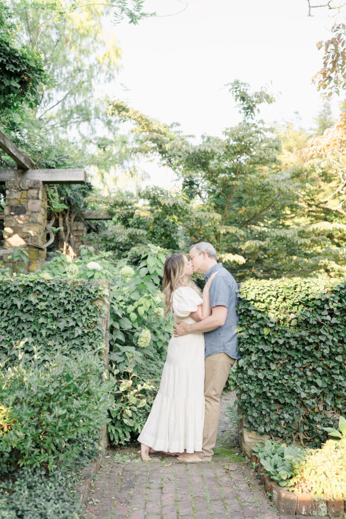 Husband and wife kiss in a secret garden setting.