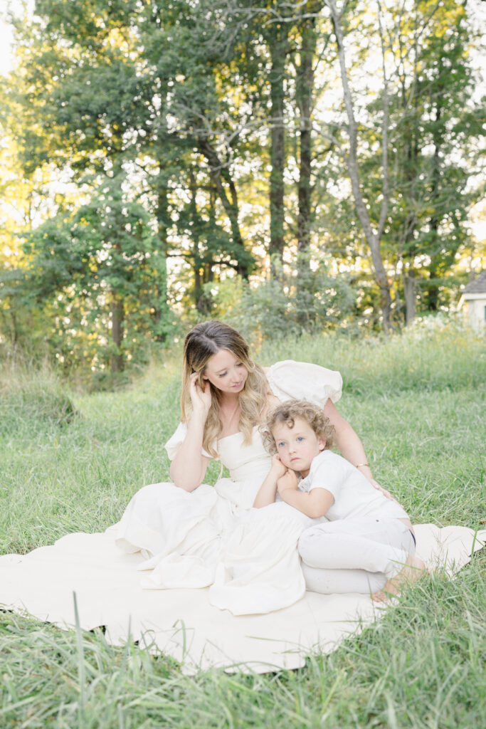 A mom and her son dressed in white sit on a blanket on Princeton University campus.