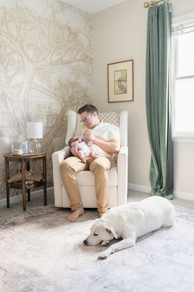 Father and newborn girl during an at-home newborn session in Collingswood with their dog.
