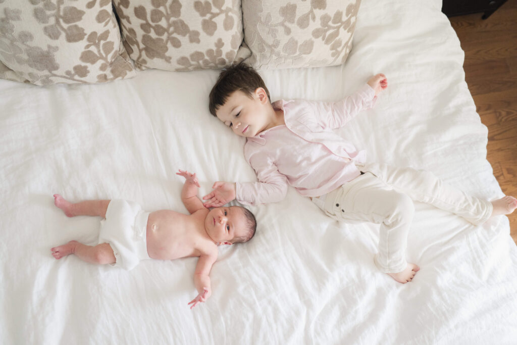 Toddler big brother gently holding his newborn sibling during a lifestyle newborn session.