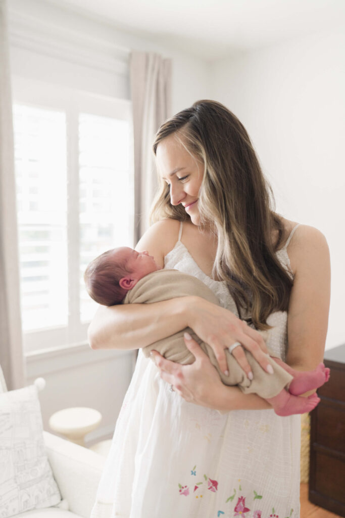 Mother cradling newborn baby in the nursery during an in-home session in Haddonfield, NJ.