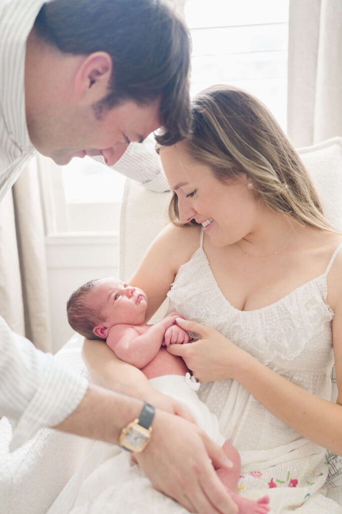 Parents cuddling their newborn baby together at home in Haddonfield.