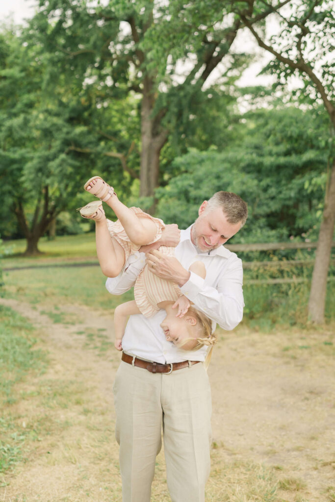 Dad holds his young daughter upside down as she laughs in Collingswood.