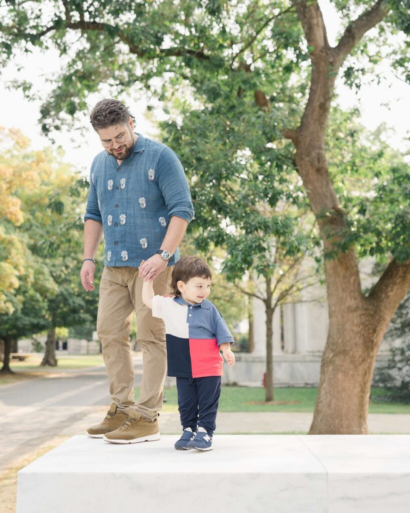 Dad holds his young son's hand as they walk.