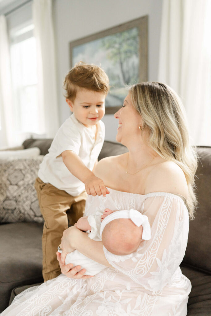 A new big brother looks at his baby sister during a spring newborn session.