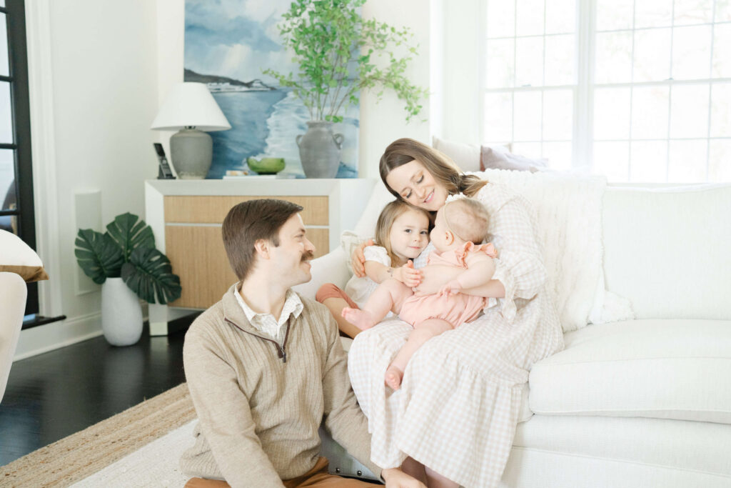 Family of four wearing neutral outfits during indoor family photo session.