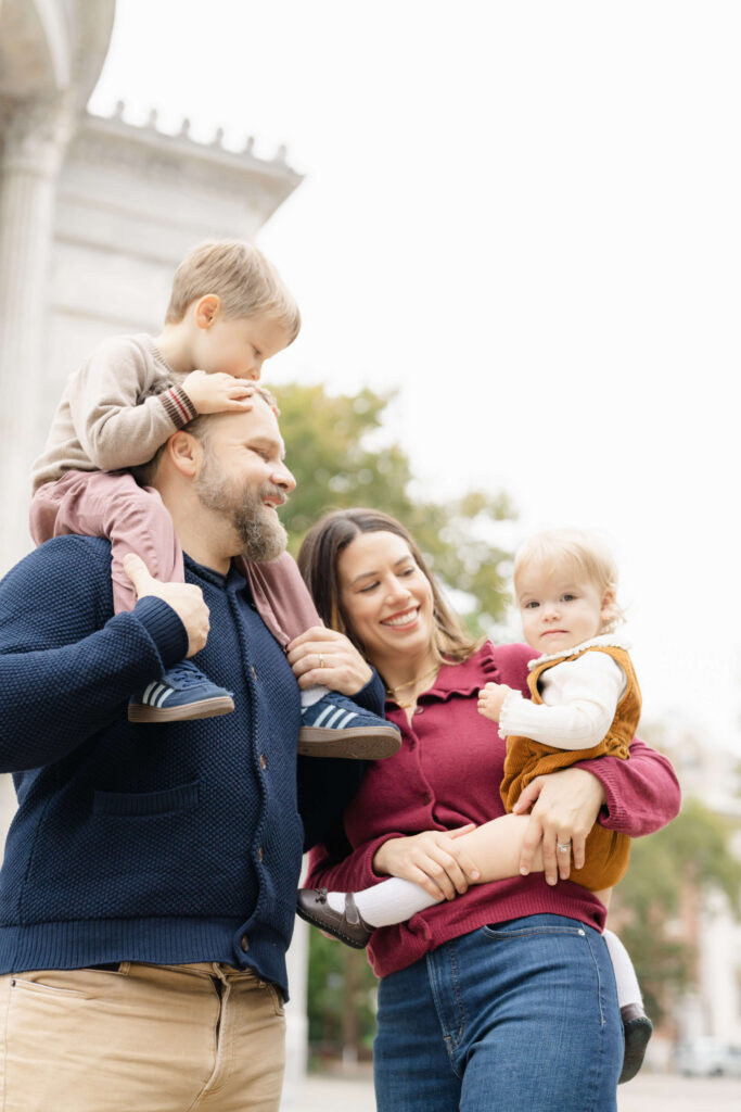 A family cuddles close and laughs outside of the Merchant Exchange Building.
